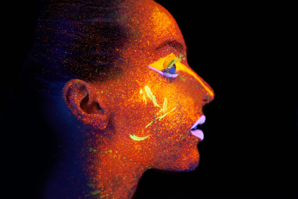 Neon profile. Side view of a young woman with neon pain on her face