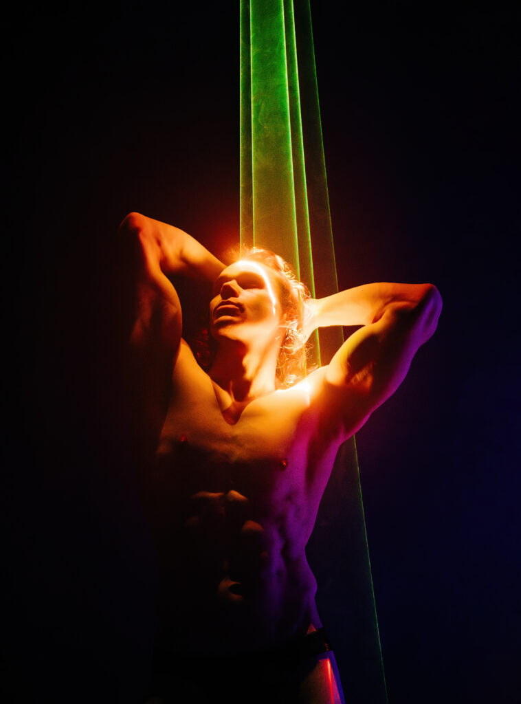 Sporty handsome man with long hair, naked torso abs portrait under colorful illumination, laser light, neon smoke club. Projection illusion mapping. Futuristic model.